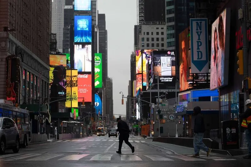 Homem caminha pela Times Square, em Nova York, quase vazia na manhã de segunda