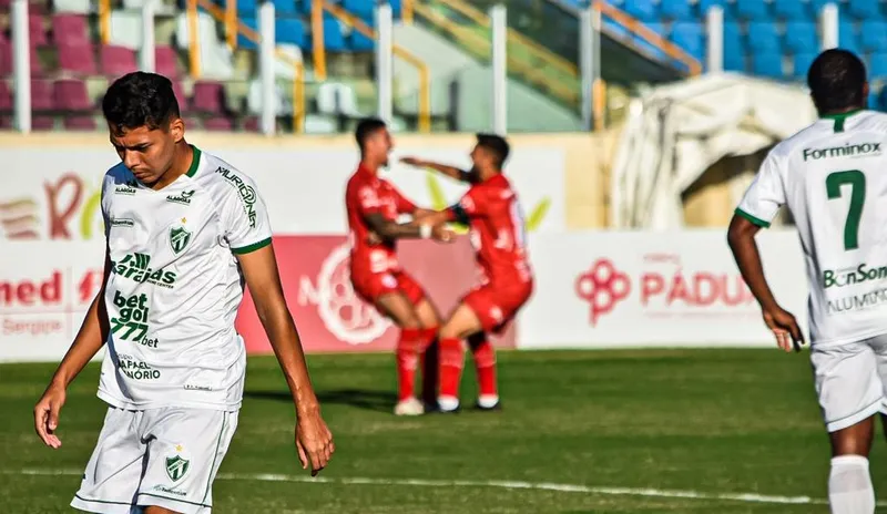 Jogadores do Sergipe comemoram o gol da equipe (ao fundo), enquanto os do Murici são o retrato da decepção