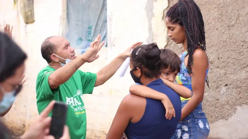No bairro Funil, pastor ora por família na ação social realizada de 8 a 11 deste mês, envolvendo adultos e crianças locais