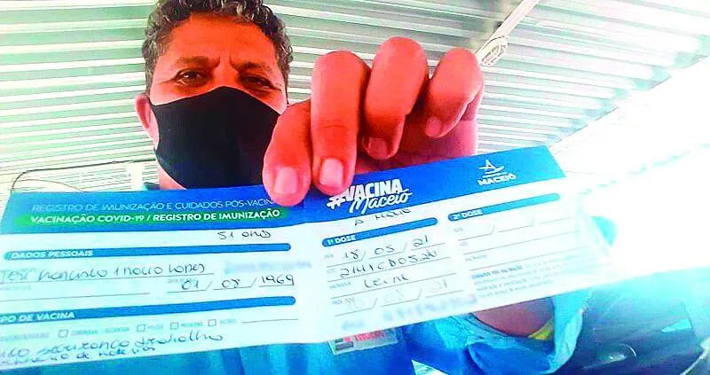 Trabalhador da construção civil exibe orgulhoso cartão de vacina