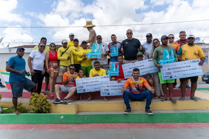 Atletas exibem o cheque da premiação da Corrida de Canoas, realizada em Porto Real do Colégio