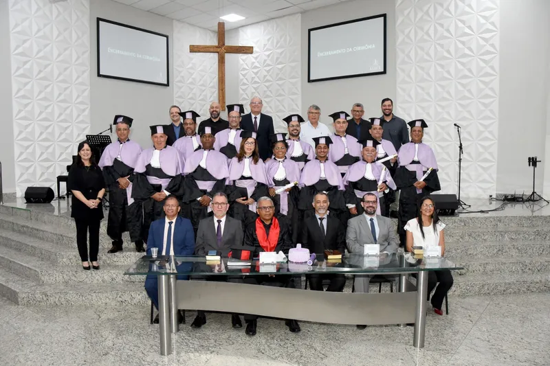 Formandos (em pé, com becas cor lilás), professores e pastores; abaixo integrantes da mesa