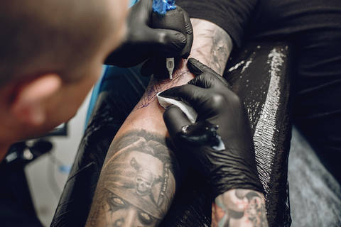 Man in a tattoo salon. Guy working. Man create a new tattoo