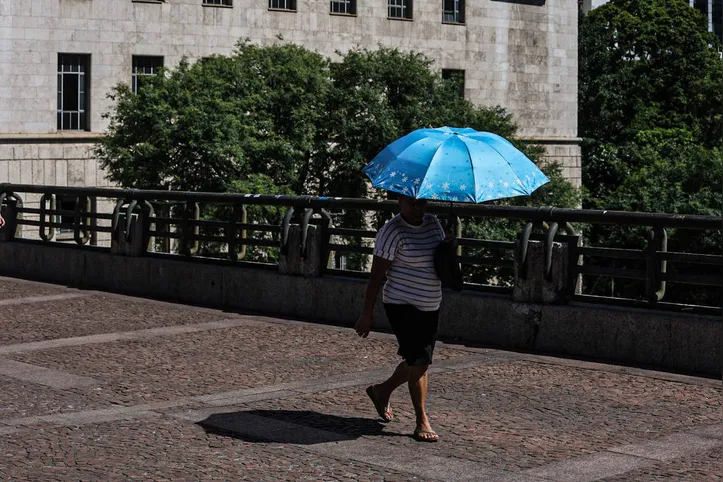 Mulher se protege do sol com um guarda-chuva no viadutor do Chá, na região central de São Paulo