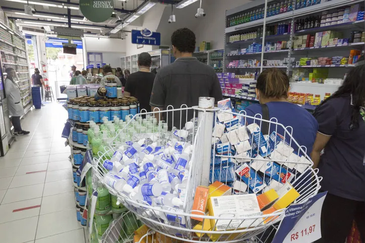 Consumidores fazem fila para comprar produtos em farmácia durante a pandemia