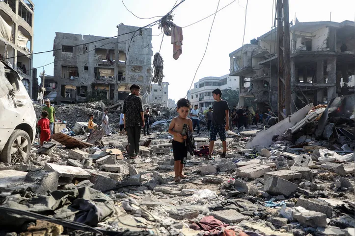 Crianças palestinas sobre escombros de prédios destruídos